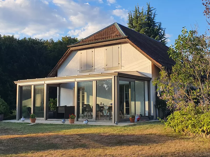 veranda bioclimatique vue de loin adossée à une grande maison